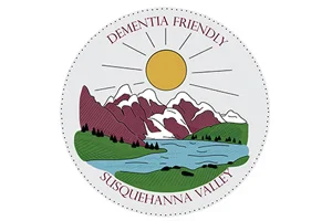 Circular logo with mountains, lake, trees, sun, and text 'Dementia Friendly Susquehanna Valley'. | DEMENTIA FRIENDLY SUSQUEHANNA VALLEY | DEMENTIA FRIENDLY SUSQUEHANNA VALLEY | DEMENTIA FRIENDLY SUSQUEHANNA VALLEY | DEMENTIA FRIENDLY SUSQUEHANNA VALLEY | DEMENTIA FRIENDLY SUSQUEHANNA VALLEY